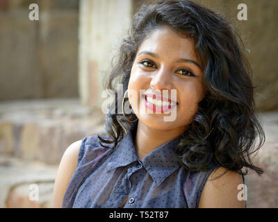 Jolie jeune femme indienne avec hoop earrings et de beaux cheveux pose pour la caméra à New Delhi un paisible Jardins Lodhi. Banque D'Images