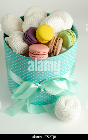 Macarons macarons colorés ou en français et dans les meringues boîte cadeau turquoise sur fond blanc. Carte de vœux. Banque D'Images