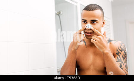 Jeune homme l'application de patch nez devant un miroir Banque D'Images