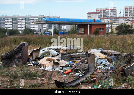Décharge de la ville illégale dans l'herbe sèche, près de la station d'essence. Périphérie d'une grande ville. Banque D'Images