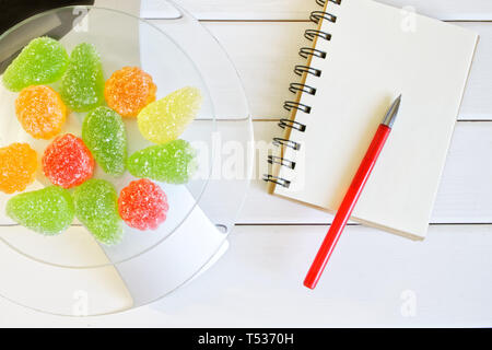Marmelade multicolores sur les balances de cuisine à côté d'un ordinateur portable et un stylo plume. Le dépouillement et l'enregistrement de la quantité de protéines, de calories et de matières grasses dans l'alimentation Banque D'Images