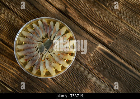 Tranches de filet de hareng scandinave avec les épices dans un pot en plastique. Réglage de la table sur une table rustique en bois faites de planches de pin Banque D'Images