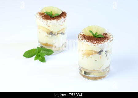 Concept de dessert italien. Tiramisu d'ananas sur une tasse de verre sur fond blanc. Décoration feuilles de menthe. Banque D'Images