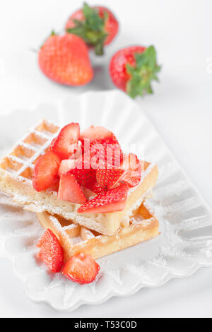Belgique waffers avec du sucre en poudre et les fraises sur une plaque en céramique sur le tableau blanc. Des wafers. Banque D'Images