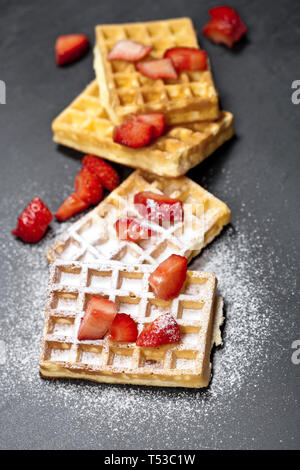Belgique waffers avec des fraises et du sucre en poudre sur tableau noir l'arrière-plan. Banque D'Images
