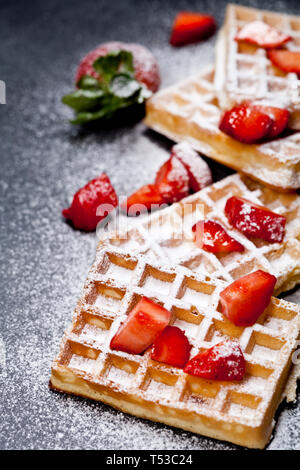 Belgique waffers avec des fraises et du sucre en poudre sur tableau noir l'arrière-plan. Gaufrettes frais cuit avec copie espace. Banque D'Images