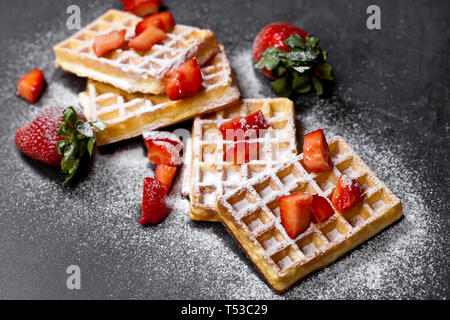 Belgique waffers avec des fraises et du sucre en poudre sur tableau noir l'arrière-plan. Gaufrettes frais cuit avec copie espace. Banque D'Images