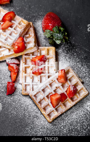Belgique waffers avec des fraises et du sucre en poudre sur tableau noir l'arrière-plan. Banque D'Images