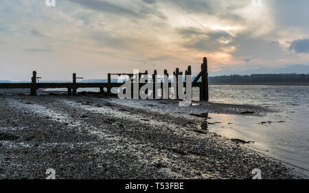 Pier abandonnés sur les rives de la Détroit de Menai au lever du soleil. Voir d'Anglesey, dans le Nord du Pays de Galles, Royaume-Uni. Prise le 9 avril 2019. Banque D'Images