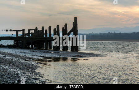 Pier abandonnés sur les rives de la Détroit de Menai au lever du soleil. Voir d'Anglesey, dans le Nord du Pays de Galles, Royaume-Uni. Prise le 9 avril 2019. Banque D'Images