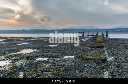 Pier abandonnés sur les rives de la Détroit de Menai au lever du soleil. Voir d'Anglesey, dans le Nord du Pays de Galles, Royaume-Uni. Prise le 9 avril 2019. Banque D'Images