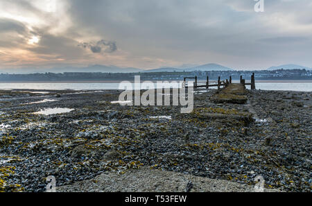 Pier abandonnés sur les rives de la Détroit de Menai au lever du soleil. Voir d'Anglesey, dans le Nord du Pays de Galles, Royaume-Uni. Prise le 9 avril 2019. Banque D'Images