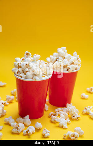 Pop corn salé frais dans deux conteneurs carton rouge, fond de couleur jaune Banque D'Images