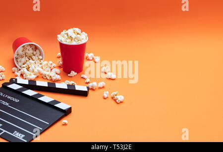 Film de cinéma concept. Pop corn salé frais et movie clapper board, couleur orange, l'arrière-plan Banque D'Images