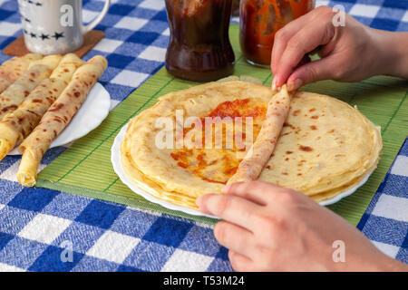 Les mains des femmes accueil remplissage ou crêpes crêpes des balkans rolls avec de la confiture ou de la marmelade. Faire rapidement de petit-déjeuner pour les enfants. Banque D'Images