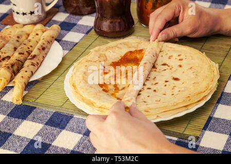 Les mains des femmes accueil remplissage ou crêpes crêpes des balkans rolls avec de la confiture ou de la marmelade. Faire rapidement de petit-déjeuner pour les enfants. Banque D'Images