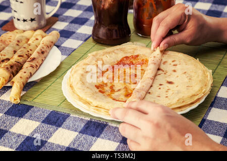 Les mains des femmes accueil remplissage ou crêpes crêpes des balkans rolls avec de la confiture ou de la marmelade. Faire rapidement de petit-déjeuner pour les enfants. Effet de couleur. Banque D'Images