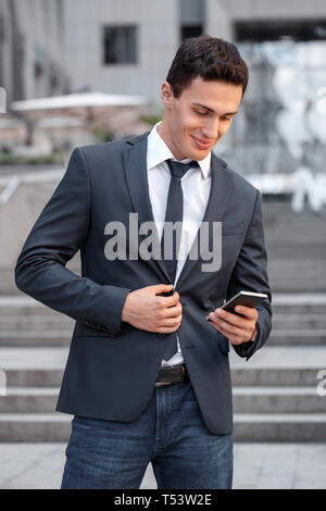 Entreprise Jeune homme debout sur la ville rue de la navigation internet sur smartphone joyeux sourire Banque D'Images