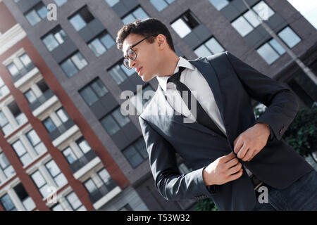 Man wearing eyeglasses debout sur le bouton jusqu'à la rue de la ville de côté Vue de dessous réfléchie Banque D'Images