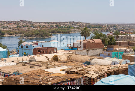 Vue sur la rivière du Nil à Assouan Egypte à partir de la berge par paysage rural paysage avec Maisons de village nubien en premier plan Banque D'Images