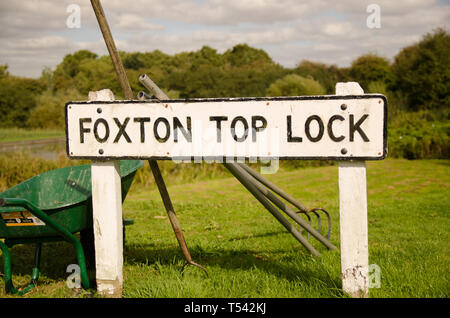 Une plaque de rue à Foxton Locks dans le Leicestershire en regard d'une brouette verte Banque D'Images