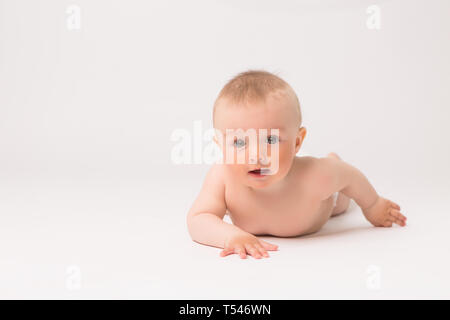 Cute little baby boy aux couches de ramper sur fond blanc lumineux,photo de ramper bébé curieux sur backgroubd blanc Banque D'Images