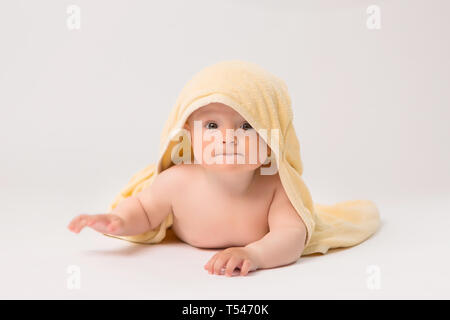 Bébé garçon avec towel on head jaune sur fond blanc, Portrait of cute Caucasian bébé nouveau-né. L'enfant est enveloppée dans une serviette douce jaune après Banque D'Images