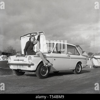 1967, historiques, à l'extérieur à un chantier, nous voyons une jeune femme portant un cardigan en laine et jupe assis ou posant dans le coffre d'une automobile, le sport Sunbeam version sportive de la célèbre petite voiture, l'HIllman Imp. Le moteur a été à l'arrière et ainsi le coffre était à l'avant. L'Hillman Imp est une petite voiture à moteur arrière faites par Rootes Group et son successeur Chrysler Europe de 1963 à 1976 a été l'un concurrent dans la catégorie des petites voitures à la British Leyland Mini. Banque D'Images