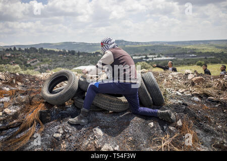 Kafr Qaddum, Qalqilya, Palestine. Apr 19, 2019. Vu palestinienne se mettre à couvert à côté de pneumatiques pendant les affrontements.palestiniens se sont affrontés avec l'armée israélienne au cours de la démonstration dans le village de Kafr Qaddum. Palestiniens mars chaque vendredi et samedi dans le village de Kafr Qaddum depuis 2011 en raison de la fermeture de l'une de leurs routes et la confiscation des terres par les autorités israéliennes. Ces décisions ont été prises pour étendre la colonie de Kedumim. Grâce à cette route, les Palestiniens ont été en mesure de parvenir à la principale ville de Naplouse, en 15 minutes, maintenant il faut plus de 45 minutes. (Crédit Image : © Banque D'Images