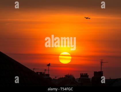 Londres, Royaume-Uni. 20 avril, 2019. Avion décolle à partir de Heathrow à mesure que le soleil se couche sur les toits de banlieue dans un ciel orange clair après un jour de ciel dégagé et les températures estivales au cours de la flambée de semaine de Pâques. Credit : Malcolm Park/Alamy Live News. Banque D'Images