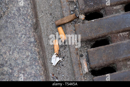 Hambourg, Allemagne. 18 avr, 2019. Les mégots sont situées sur la rue sur un couvercle de trou d'homme. Déchets de Hambourg watchers ont imposé autour de 6000 mises en garde et des amendes pour l'élimination illégale de déchets dans l'année. Selon un porte-parole, environ la moitié d'entre eux ont été dirigés contre les fumeurs qui simplement feuilleter leurs cigarettes sur la rue ou dans la nature. (Dpa 'presque 6000 amendes pour les pourboires et de chewing-gum sur les trottoirs de Hambourg") Crédit : Daniel Reinhardt/dpa/Alamy Live News Banque D'Images