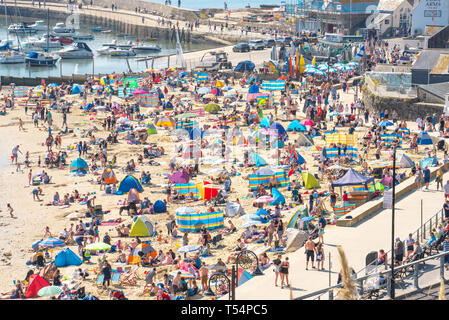 Lyme Regis, dans le Dorset, UK. 21 avril 2019. Météo France : visiteurs affluent à la plage bondée à Lyme Regis pour se prélasser au soleil brûlant le dimanche de Pâques. Se prélasser au soleil, une chaleur étouffante sur les plages de la ville sur une plaque à pâtisserie bank holiday weekend comme la côte jurassique rôtis au début du printemps une vague énorme début de stimuler l'économie locale. Credit : Celia McMahon/Alamy Live News. Banque D'Images