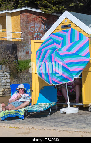 Bournemouth, Dorset, UK. 21 avr 2019. Météo France : la canicule se poursuit avec le temps ensoleillé et chaud, en tant que chef de la plage au bord de la mer pour profiter de la chaleur et du soleil à plages de Bournemouth pour les vacances de Pâques - le milieu de la matinée et les plages sont déjà obtenir paniers, comme sunseekers arriver tôt pour obtenir leur espace. Senior couple at beach hut. Credit : Carolyn Jenkins/Alamy Live News Banque D'Images