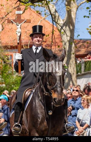 Panschwitz Kuckau, Allemagne. Apr 21, 2019. Un cavalier de Pâques avec une croix dans sa main à travers le monastère de Sankt Marienstern. Le dimanche de Pâques, plus de 1 500 cavaliers sur l'aller de village en village et proclamer le message pascal de la résurrection de Jésus Christ dans le Catholic-Sorbian Haute Lusace. Cette procession équestre a été tenue par les hommes de l'âge de 14 ans pour de nombreux siècles. Crédit : Daniel Schäfer/dpa-Zentralbild/dpa/Alamy Live News Banque D'Images