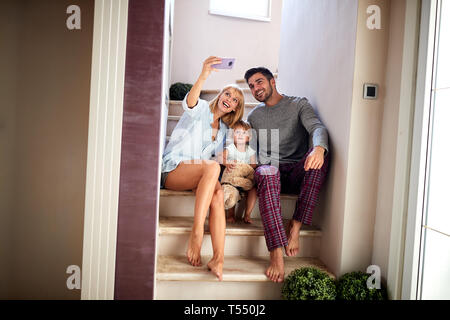 Maman en tenant avec la famille selfies, assis sur l'escalier Banque D'Images