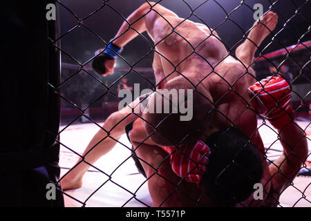 Un close-up est un professionnel MMA fighter solide tenant un rival et le frappant au cours d'un combat dans l'arène de la scène octogonale. L'ambiance et la conc Banque D'Images