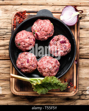 Boulettes de viande de boeuf cru vigueur-viande dans carter en fonte de fer Banque D'Images