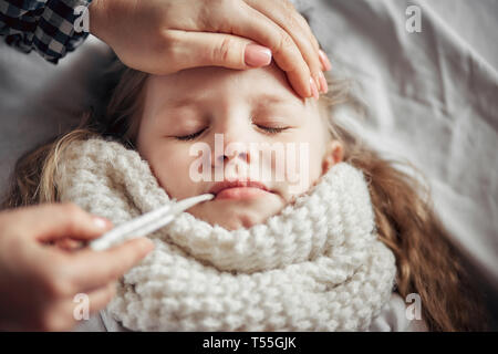 Mère attentive mesure la température d'une petite fille malade Banque D'Images