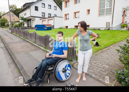 Mère et fils handicapé en attente de l'autobus scolaire Banque D'Images