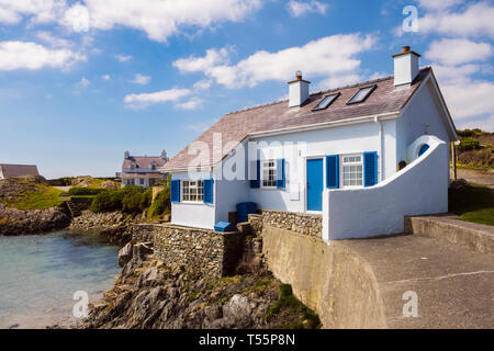 Gallois traditionnel cottage blanc et bleu donnant sur une crique rocheuse dans village côtier. Rhoscolyn, Holy Island, l'île d'Anglesey, dans le Nord du Pays de Galles, Royaume-Uni, Angleterre Banque D'Images