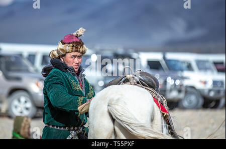 Bayan Ulgii, Mongolie, 3 octobre 2015 : kazakh man in traditional pardessus et chapeau avec son cheval dans un parking dans la nature Banque D'Images