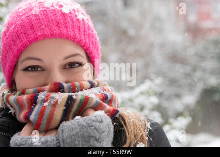 Portrait of young woman wearing woolly hat and scarf in snow Banque D'Images