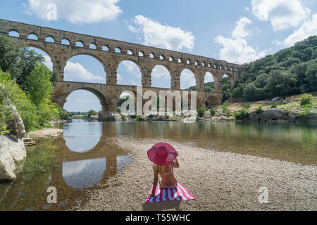 Femme portant chapeau de soleil rose par Pont du Gard à Castillon-du-Gard, France