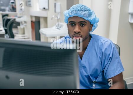 Nurse wearing filet à cheveux à l'aide d'un ordinateur à l'hôpital Banque D'Images