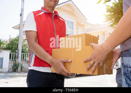 L'homme en uniforme rouge Livraison boîtes à colis remise au destinataire - service de messagerie - concept de droit Banque D'Images