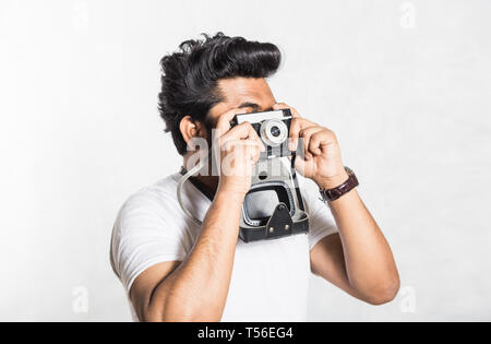 Portrait d'un beau jeune homme élégant avec barbe prendre photo sur un appareil photo vintage. Banque D'Images