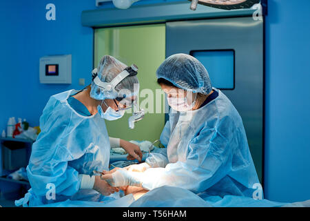 Tourné en salle d'opération, sous-mains instruments pour chirurgiens pendant le fonctionnement. Chirurgiens d'effectuer l'opération. Médecins d'effectuer la chirurgie. Banque D'Images