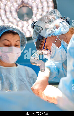 Tourné en salle d'opération, sous-mains instruments pour chirurgiens pendant le fonctionnement. Chirurgiens d'effectuer l'opération. Médecins d'effectuer la chirurgie. Banque D'Images