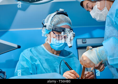 Tourné en salle d'opération, sous-mains instruments pour chirurgiens pendant le fonctionnement. Chirurgiens d'effectuer l'opération. Médecins d'effectuer la chirurgie. Banque D'Images