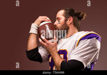 Close up portrait of American Football Player qui kiss doucement la balle Banque D'Images